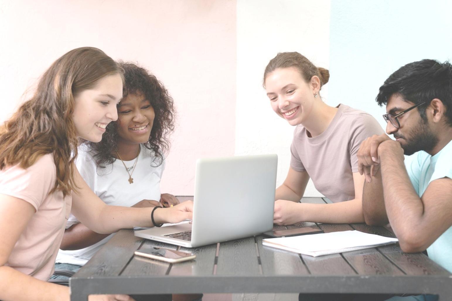 International students collaborating on budget planning with laptops and financial documents